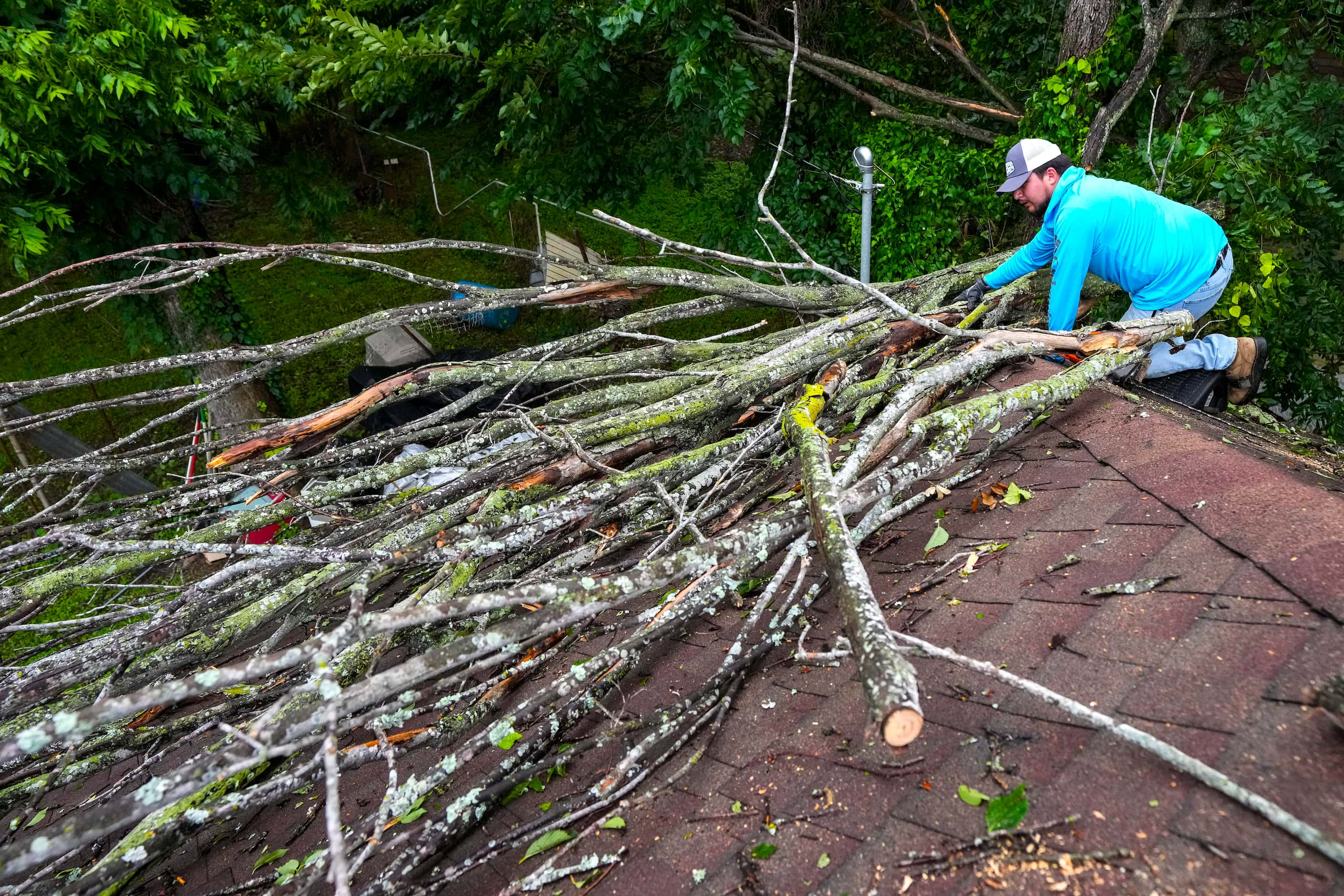 Isiah Turner, a volunteer with Trae the Truth's Relief Gang, cuts branches from a tree that...