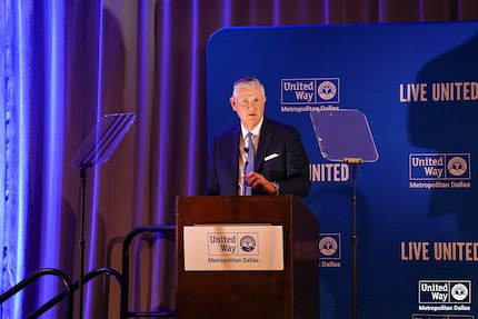 Man in suit stands at podium delivering a speech.