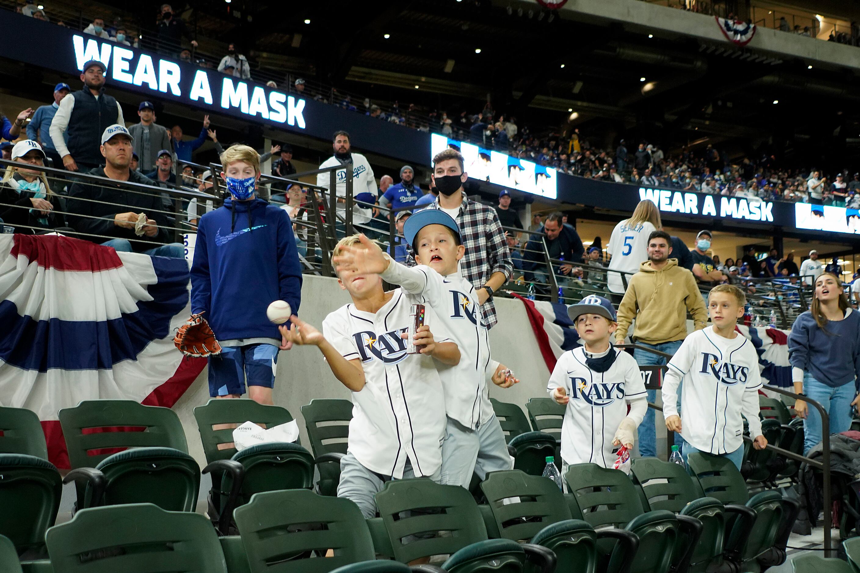 Young Tampa Bay Rays fans reach for a ball tossed into the stands by a Rays player during...
