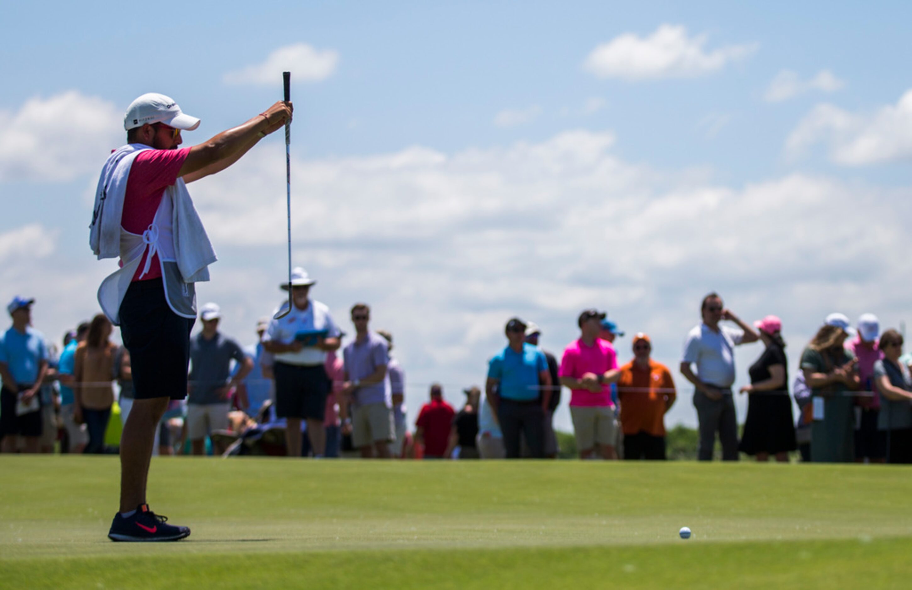 J. P. Solis, caddie for Roberto Diaz, lines up a shot on the first green during round 4 of...