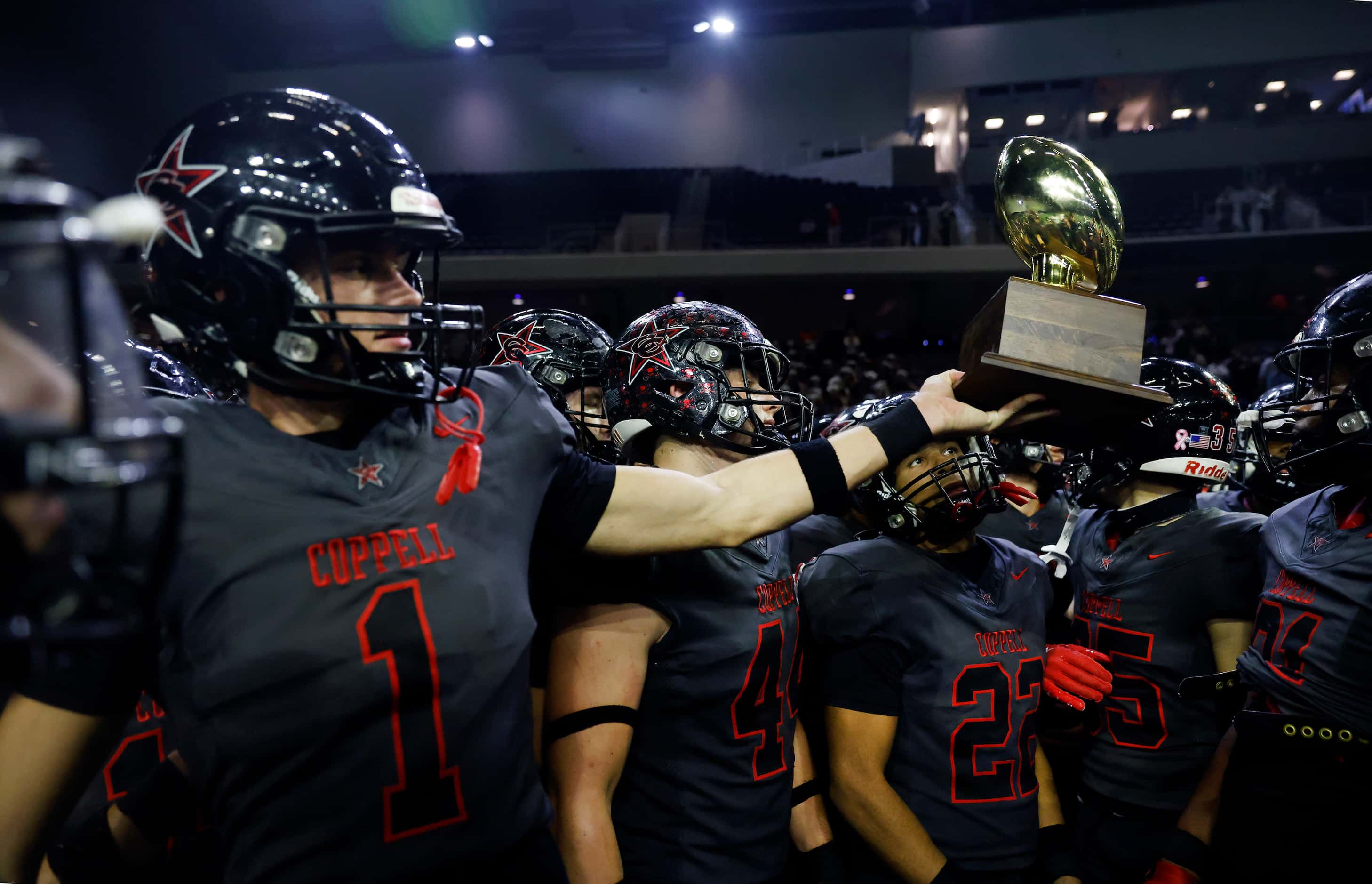 Coppell wide receiver Barton Tipton (1) holds out the Class 6A area-round playoff trophy for...