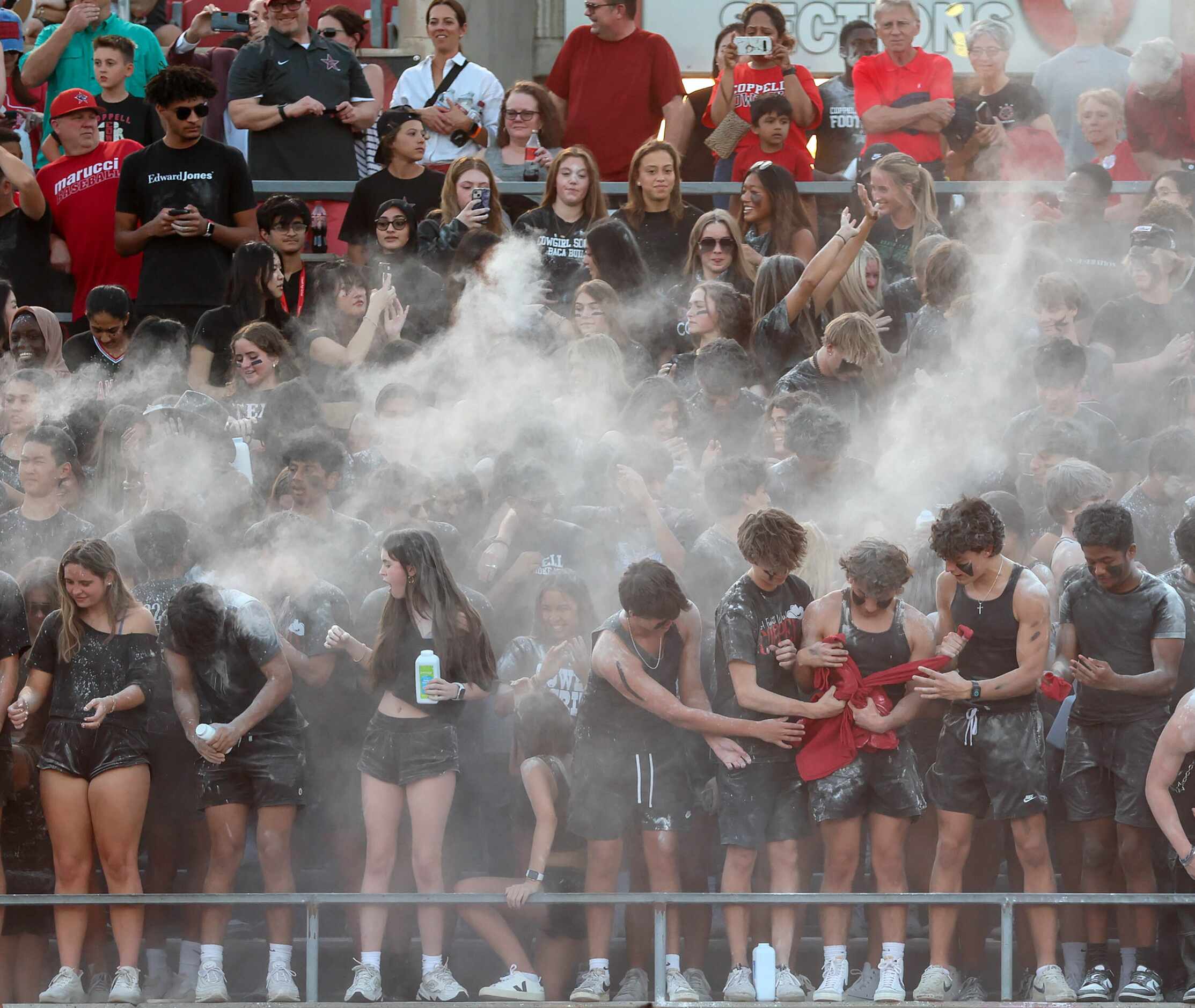 The Coppell students throw out baby powder before kickoff against Lewisville in a high...