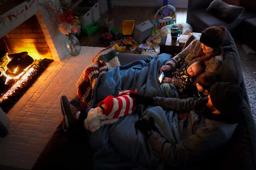 Dan Bryant and his wife Anna huddle by the fire with sons Benny, 3, and Sam, 12 weeks, along...