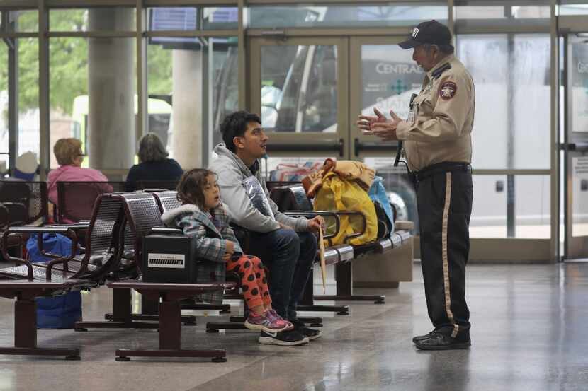 A bus terminal security guard speaks with an immigrant and his daughter in March in McAllen....