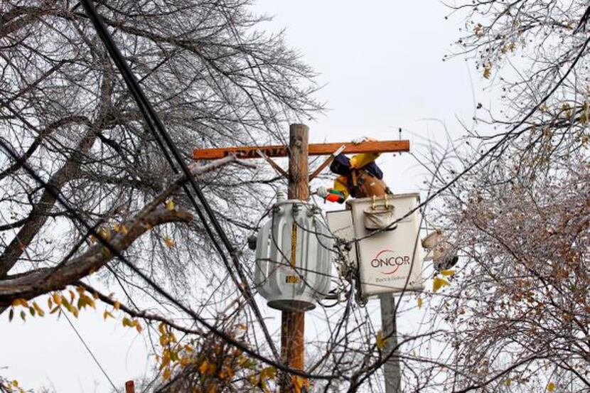 
Oncor lineman Flavio Arellano replaces a cross bar atop a utility pole after ice-laden tree...