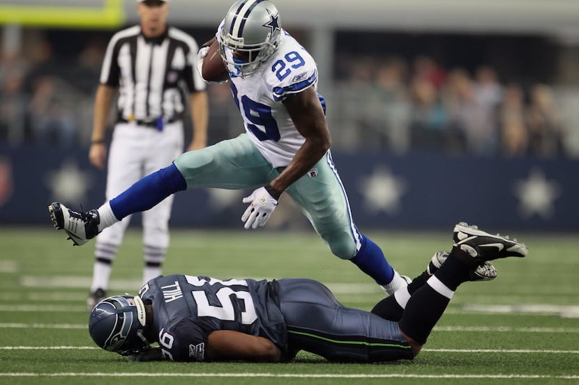 Running back DeMarco Murray #29 of the Dallas Cowboys leaps over Leroy Hill #56 of the...