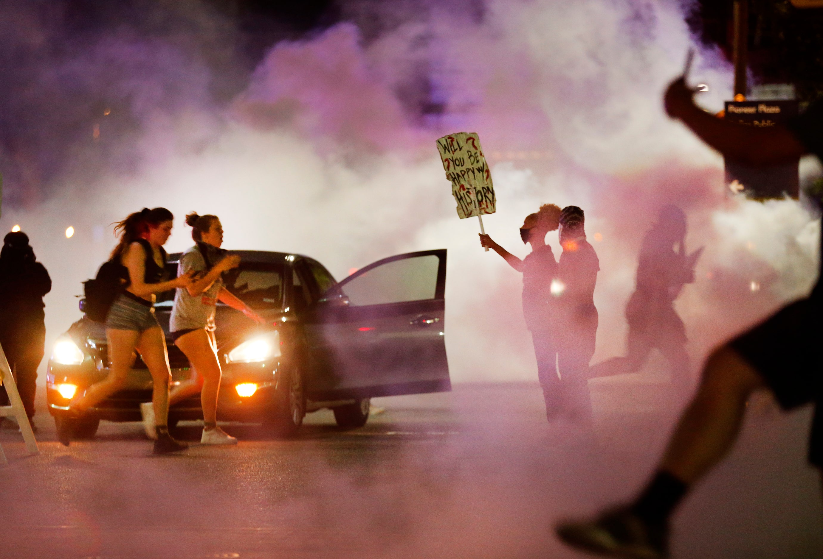 A pair of protestors are overcome with tear gas as they run from Dallas Police tactical...