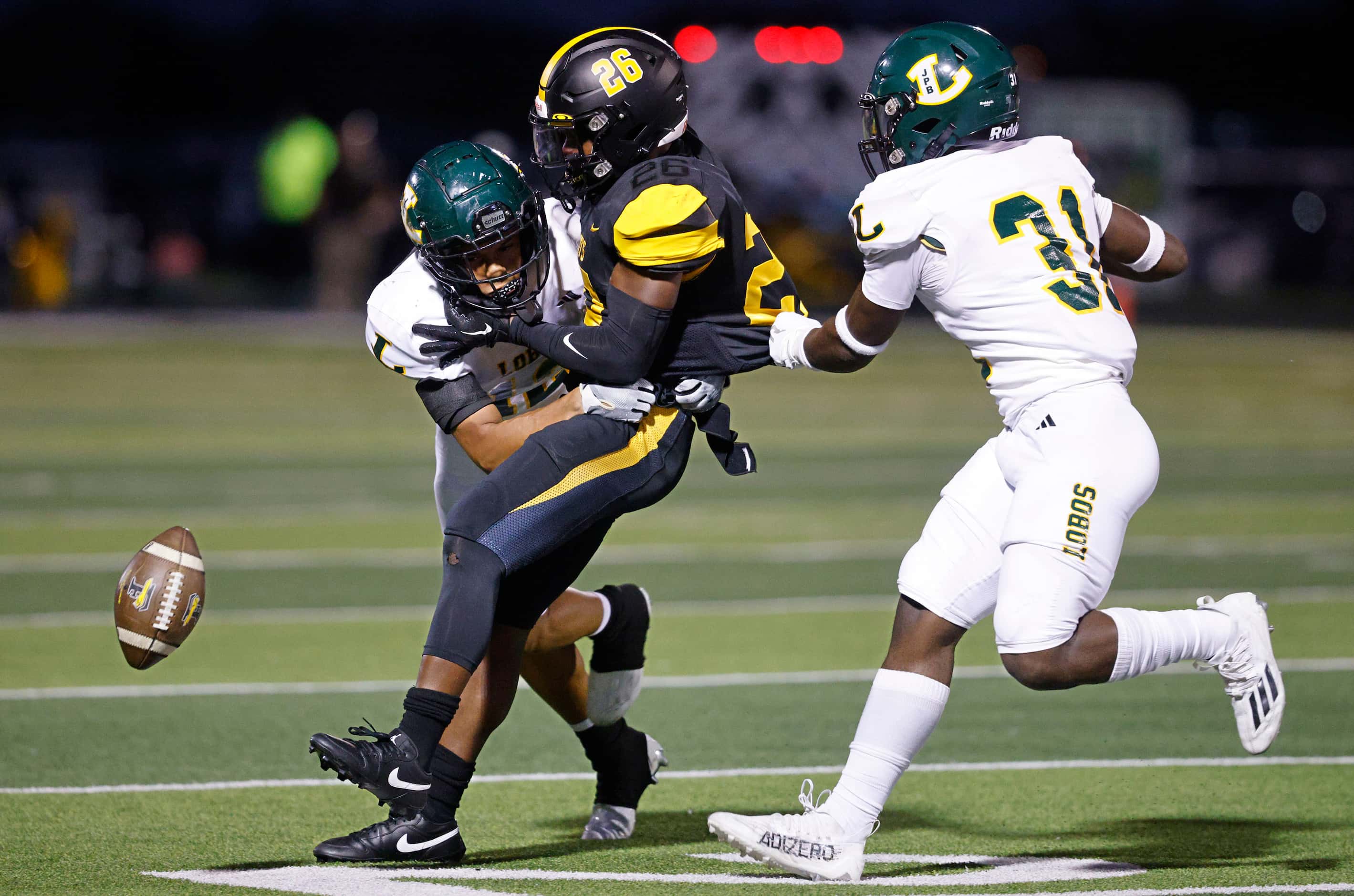 Forney's Javian Osborne (26) fumbles the ball as Longview's Bryan Peoples (12) and...