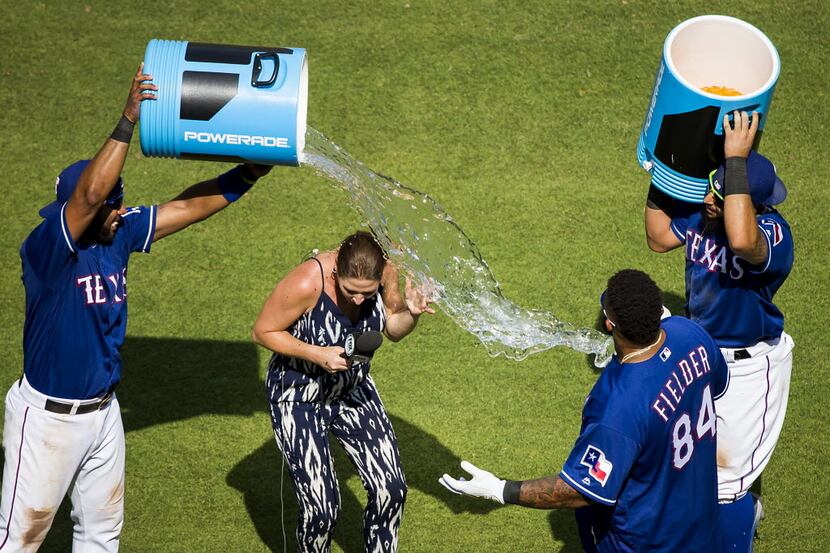Fox Sports Southwest reporter Emily Jones tries to duck away from a bucket of water tossed...