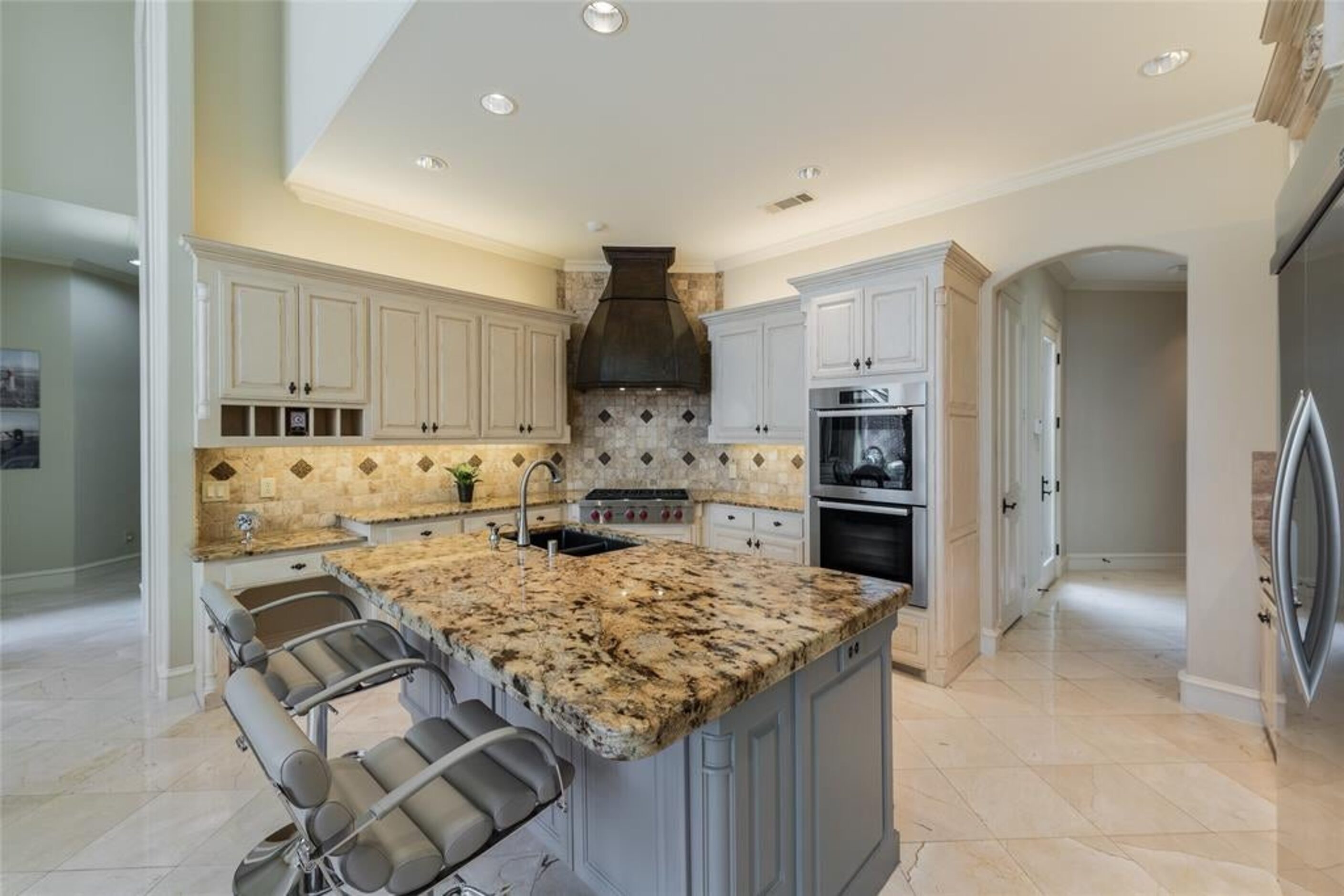 The kitchen includes a six-burner gas range and large island.