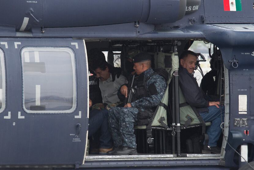 Drug trafficker Joaquin "El Chapo" Guzman, in white, is seated in a helicopter with Mexican...
