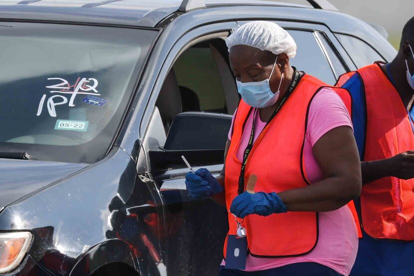 A nurse with a dose of the COVID-19 vaccine went to a vehicle where a person waited to be...