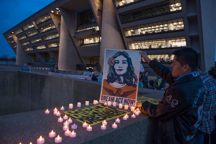 Luis Gonzalez, a DACA recipient originally from Mexico, places candles around a protest sign...