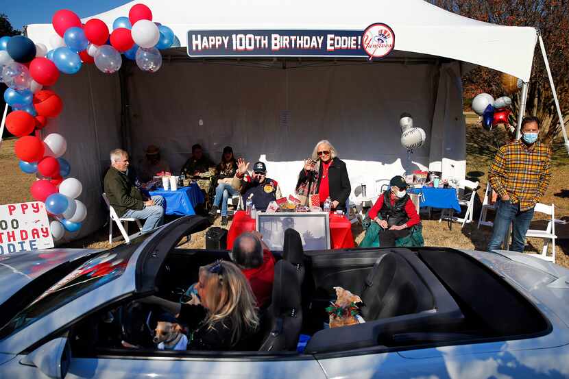 Eddie Robinson (seated)  waves to friends who deliver an early 100th birthday wish from...