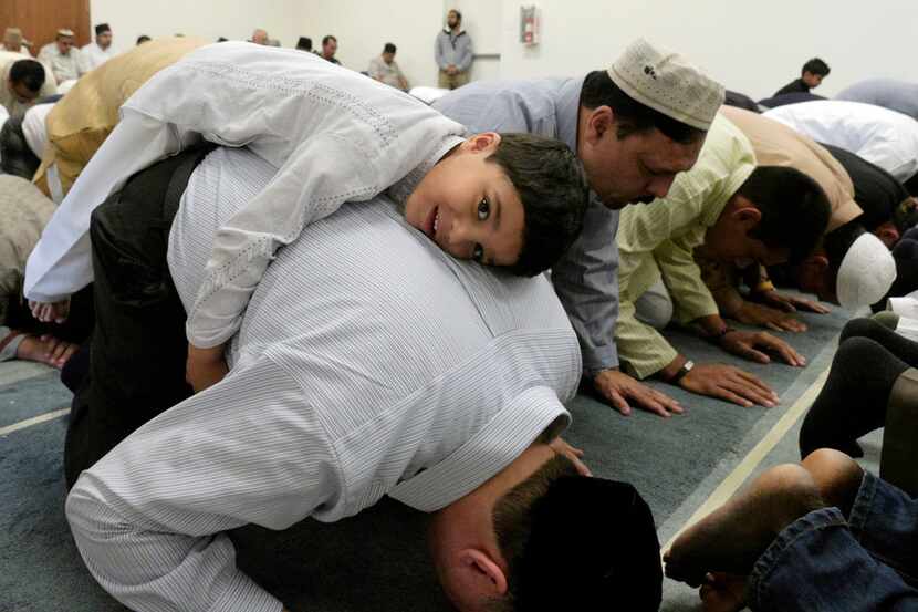 Subhan Latif, 4, rests on his father, Zubair Latif, during a prayer service for Eid-al-Fitr,...