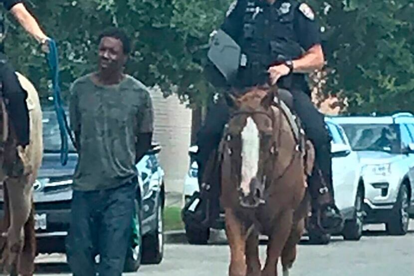 Donald Neely is walked with handcuffs and a rope by two mounted police officers in Galveston...
