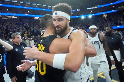 Golden State Warriors guard Stephen Curry, left, hugs Dallas Mavericks guard Klay Thompson...