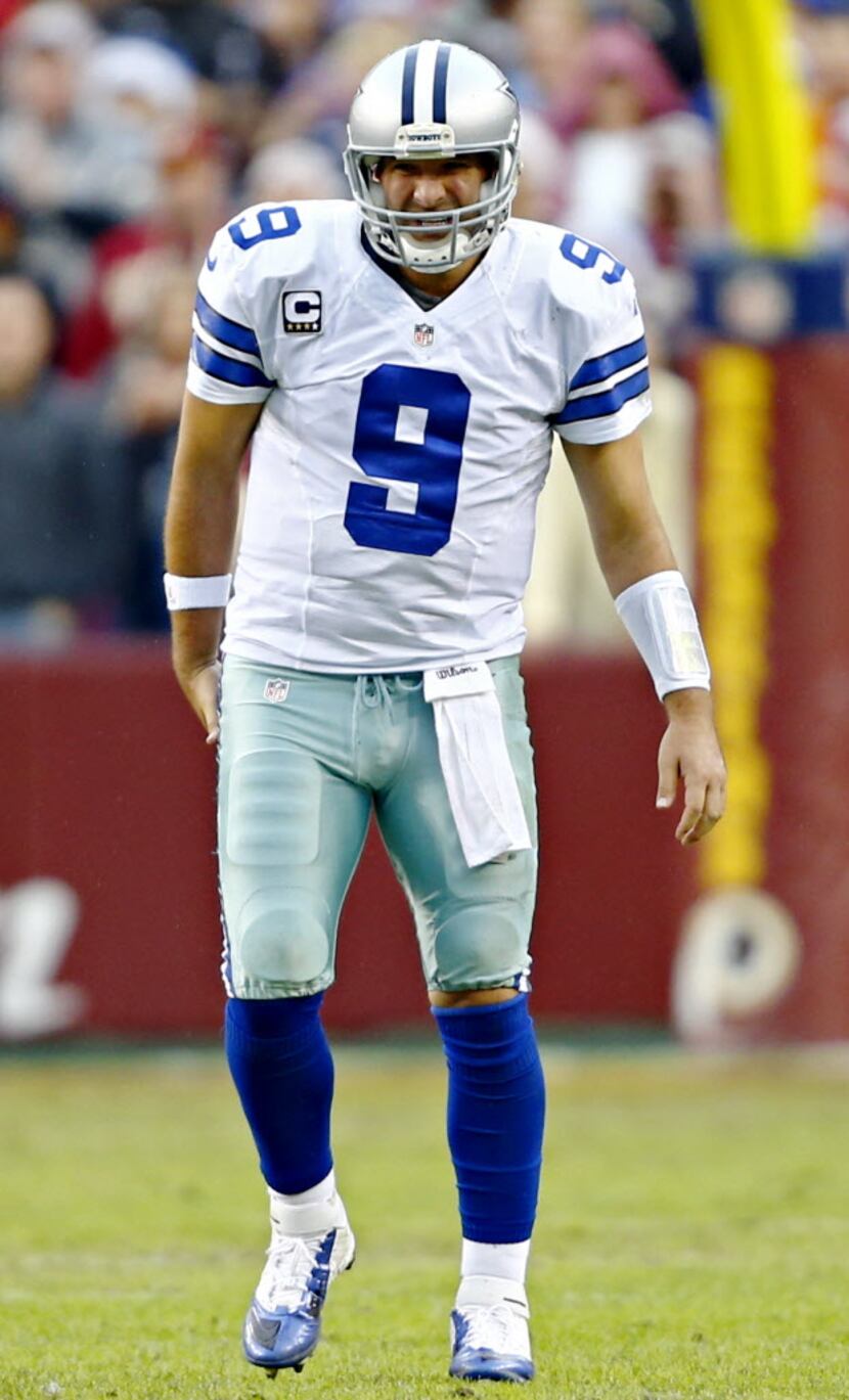 Dallas Cowboys quarterback Tony Romo appears to grab his back as he grimaces during the...