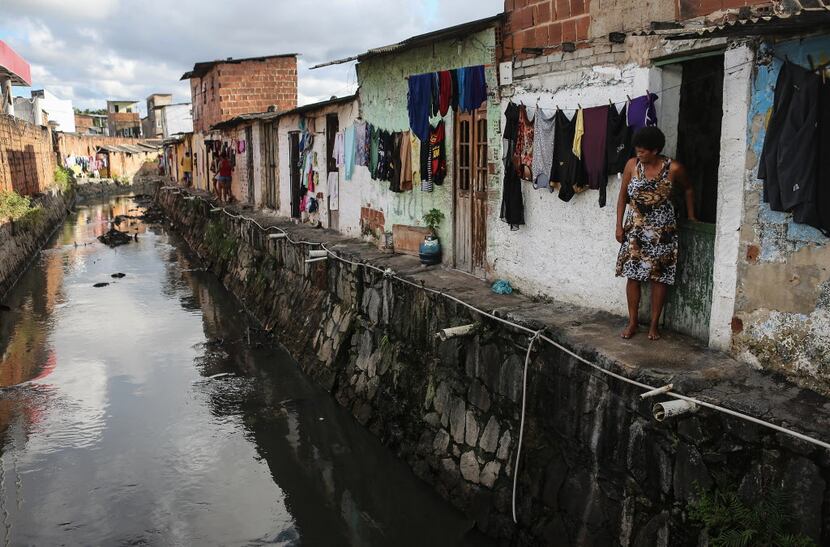  RECIFE, BRAZIL - MAY 31: A woman stands in front of her home along a polluted canal on May...