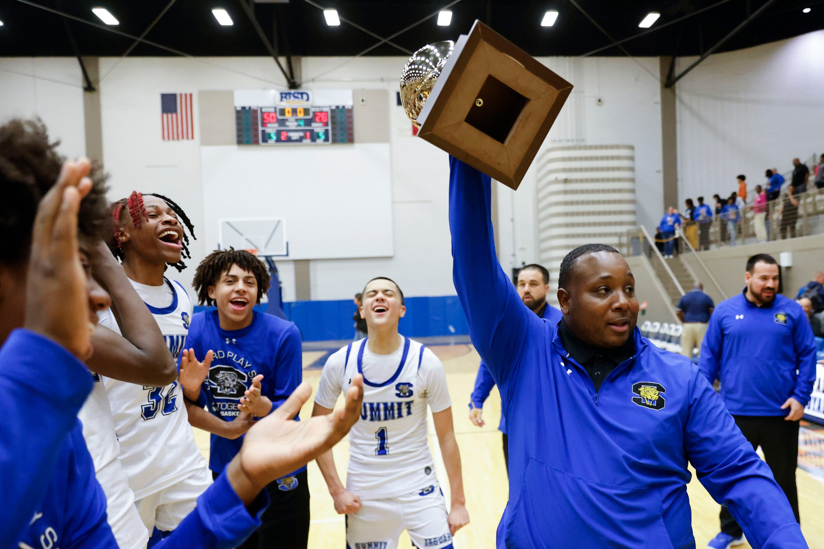 Mansfield Summit head coach Emund Prichett lifts the trophy as his team celebrate the...