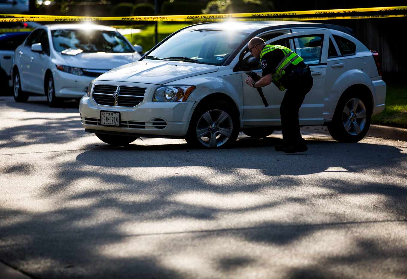 A police investigator photographs a vehicle that was carjacked, at the scene of an...