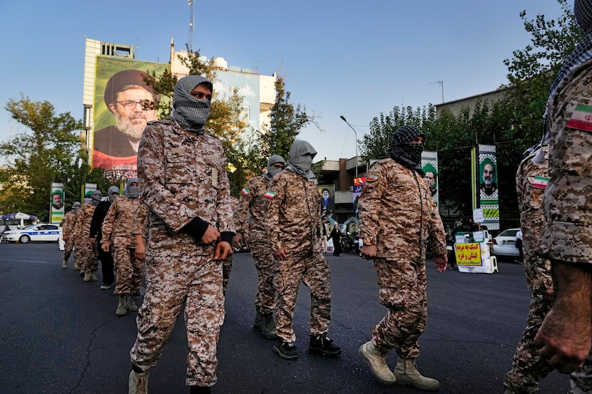 A group of the Iranian paramilitary Basij force march as they cover their faces in the...