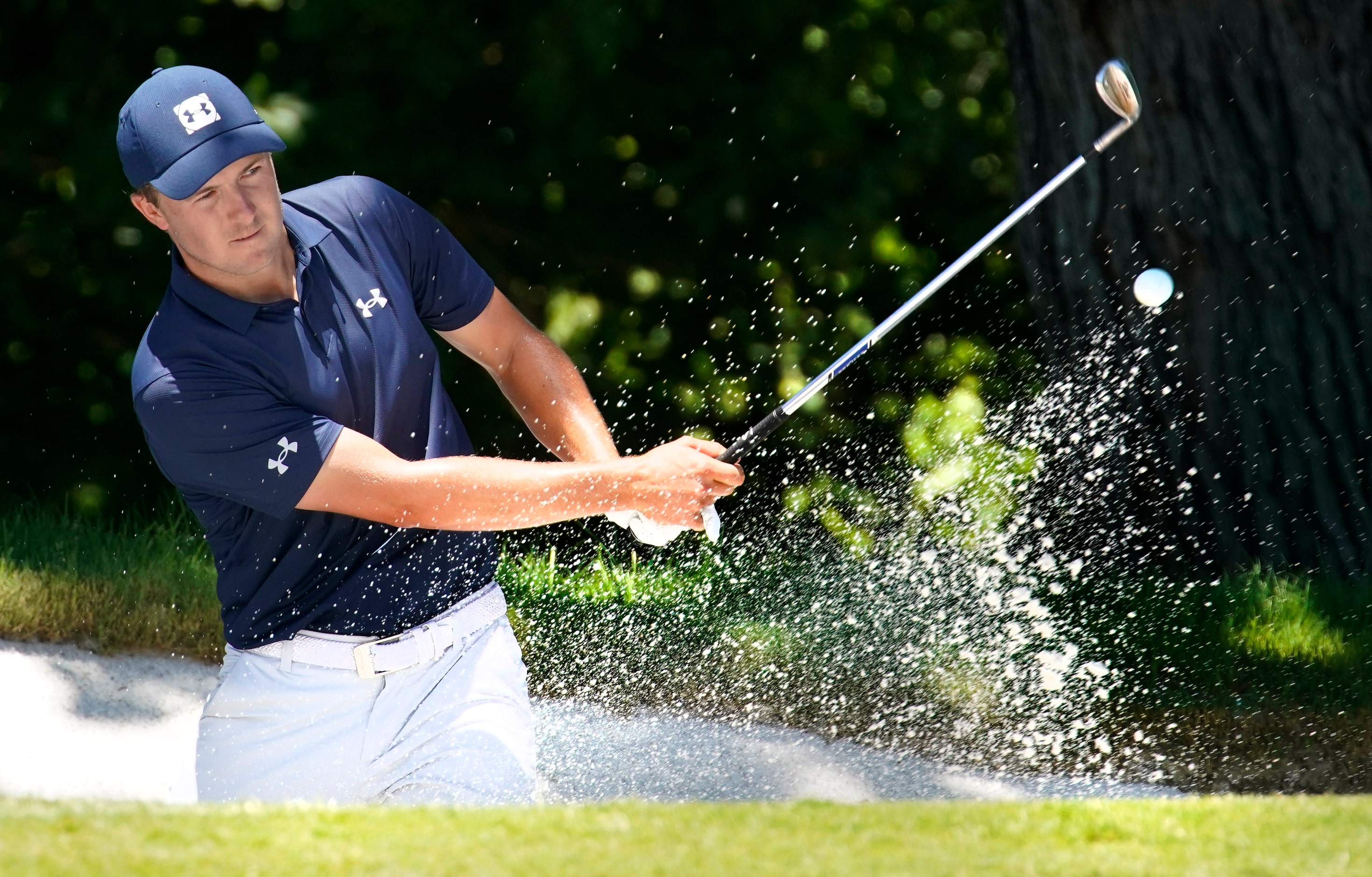 PGA Tour golfer Jordan Spieth splashes his ball out of the greenside bunker on No. 5 during...