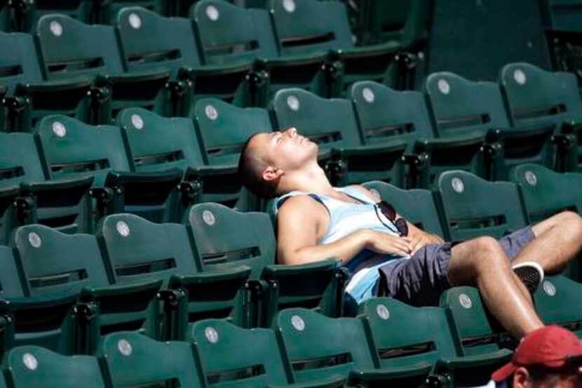 
A fan does a little sun-bathing in a seat along the left field line at a Seattle Mariners...