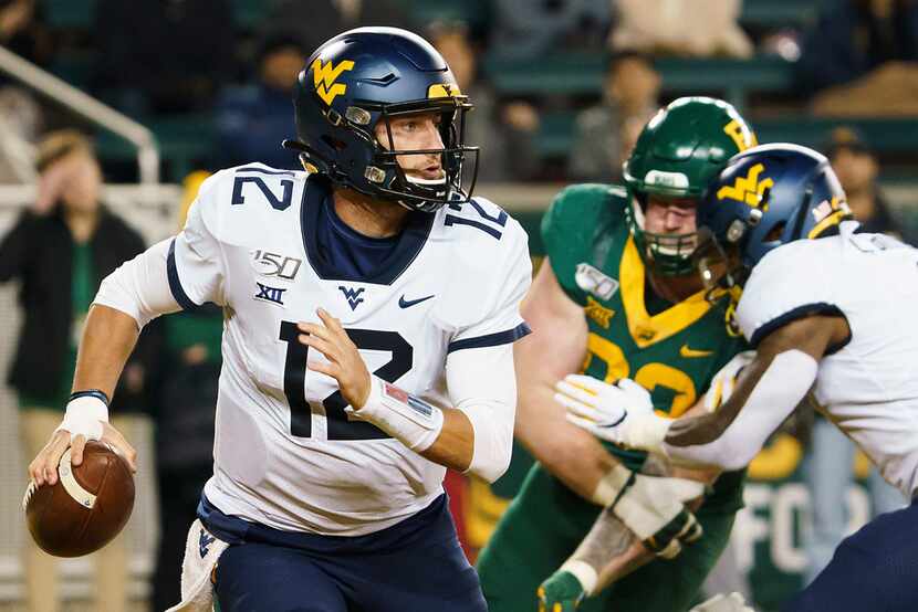 West Virginia quarterback Austin Kendall (12) scrambles away from the Baylor defense during...