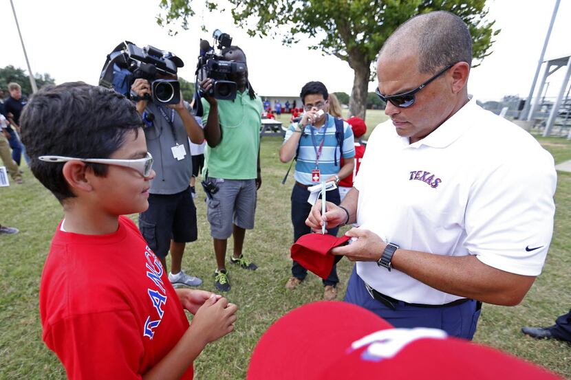 Former Rangers player Ivan Rodriguez (right) signs autographs for Steven Ramos (10) at the...