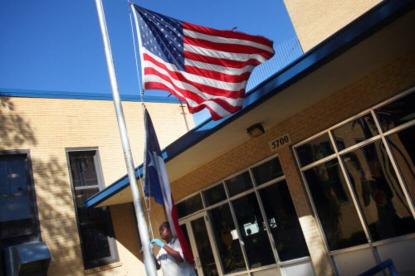 Jerry Arnold lowered the flags in front of H.S. Thompson Elementary School on Bexar Street...