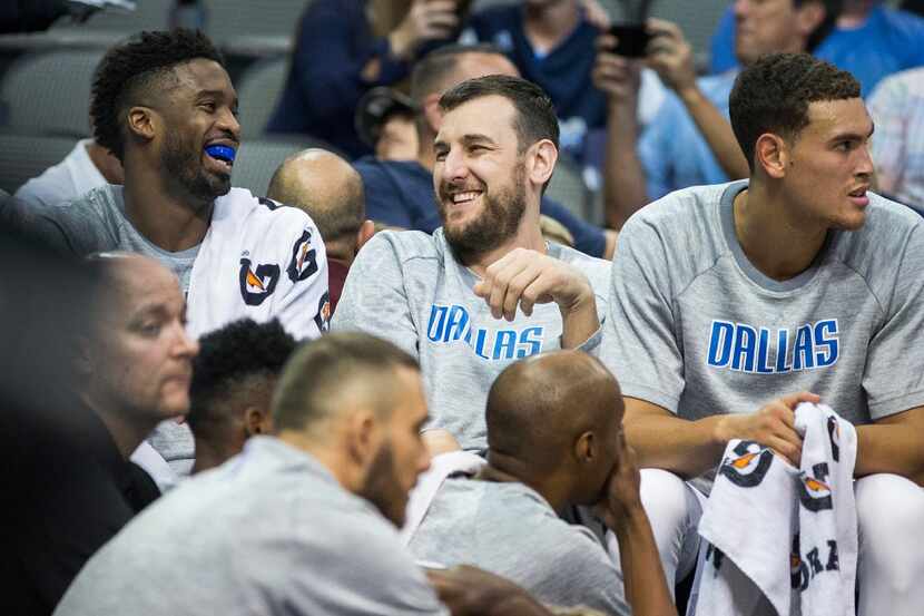 Dallas Mavericks center Andrew Bogut (center) laughs on the bench with guard Wesley Matthews...