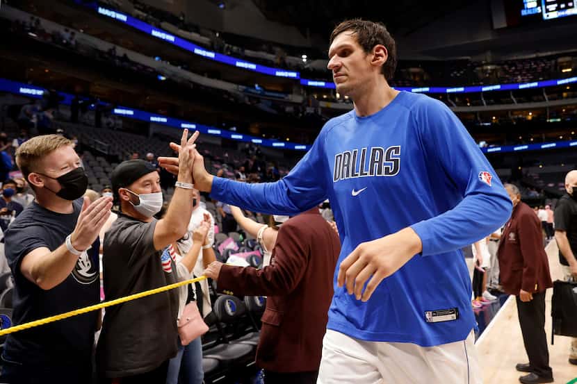 El jugador de los Mavericks de Dallas, Boban Marjanovic, saluda a aficionados con cubrebocas...