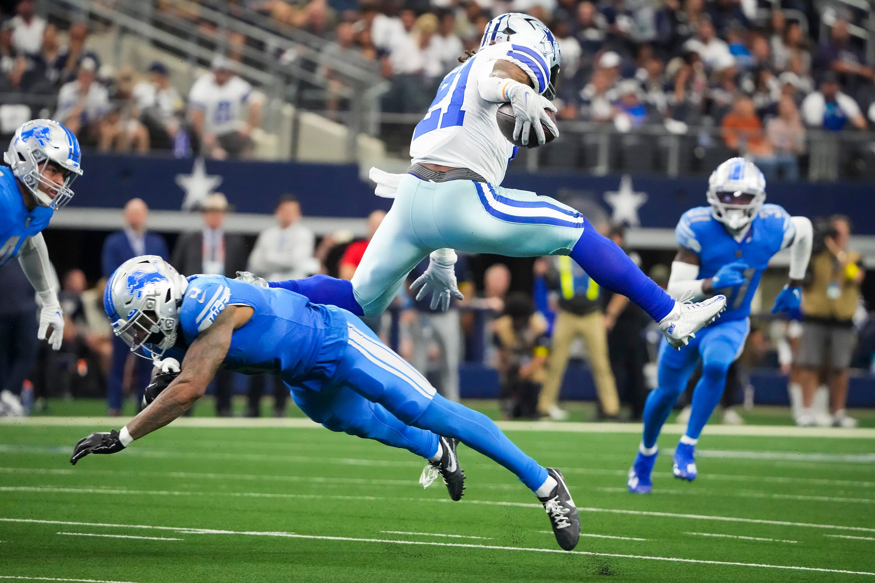 Dallas Cowboys running back Ezekiel Elliott (21) leaps over Detroit Lions safety DeShon...