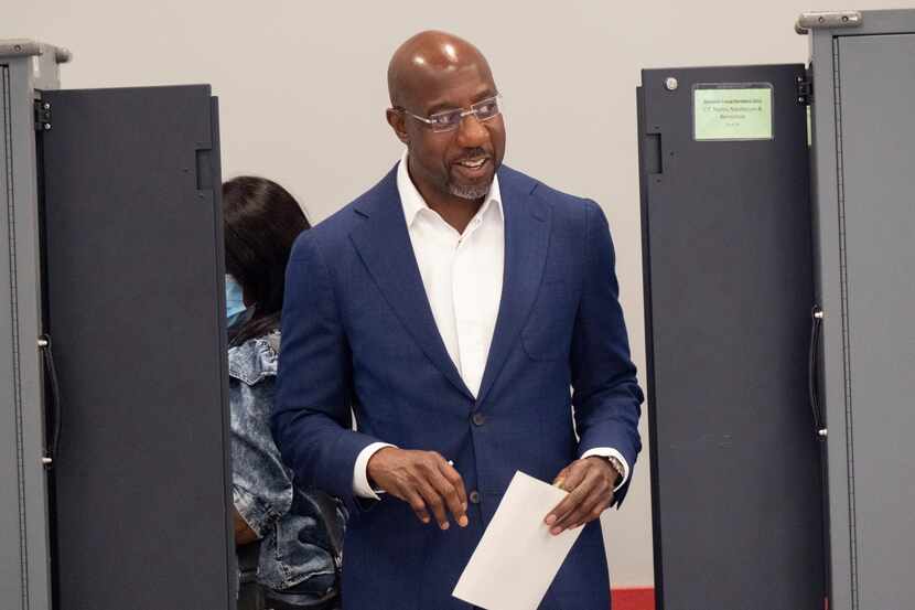 Sen. Raphael Warnock, D-Ga., walks away from a voting machine after marking his ballot on...