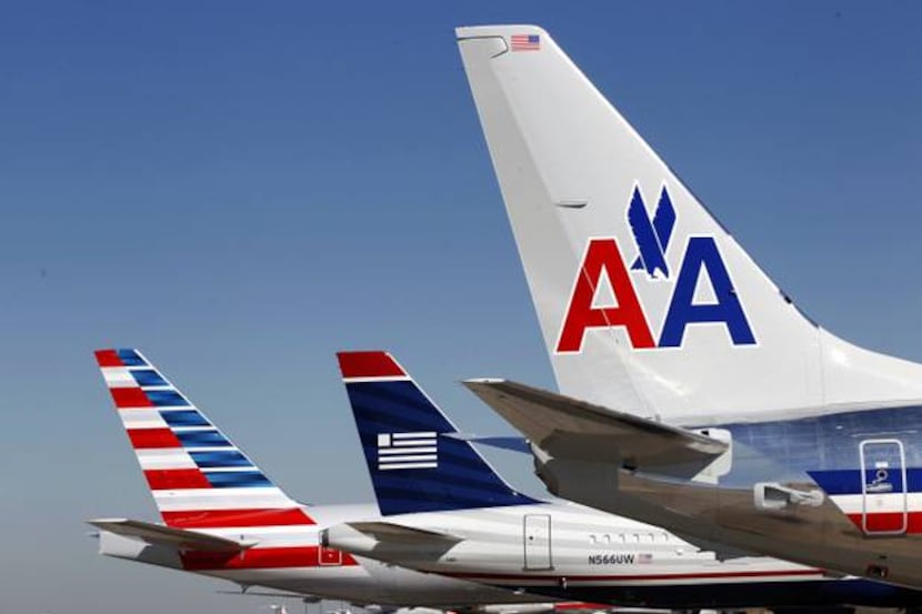  American Airlines and US Airways tails line up at an airport.
