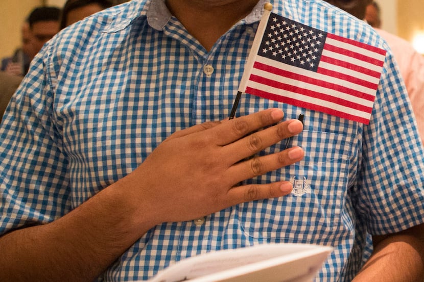 Sanjit Dhakal, from Nepal, places his hand and flag over his heart as he recites the Pledge...