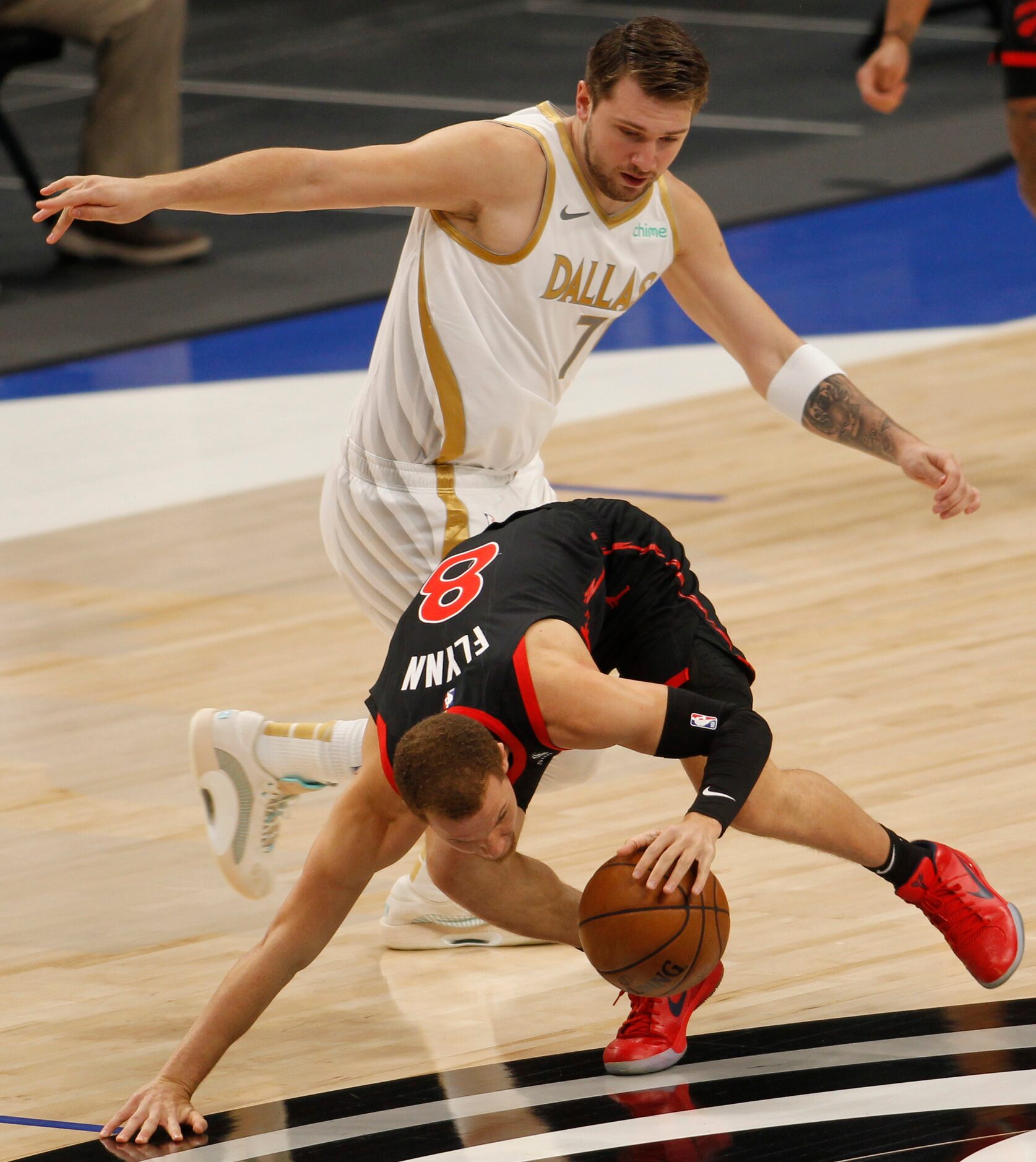 Toronto point guard Malachi Flynn (8) goes low to escape the defense of Dallas point guard...