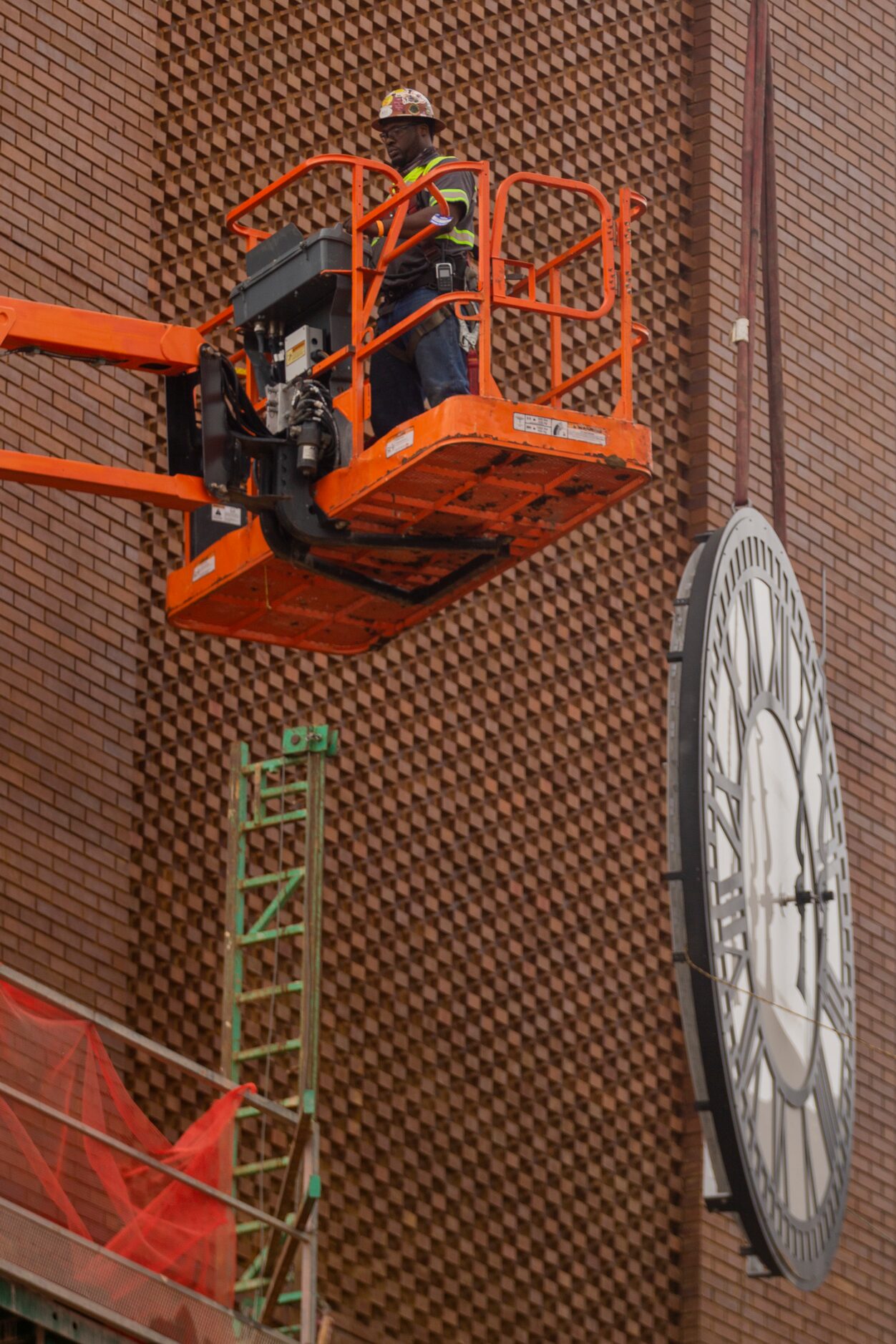 A worker from MEI Rigging & Crating works to install a 12-foot glass clock on the Grapevine...