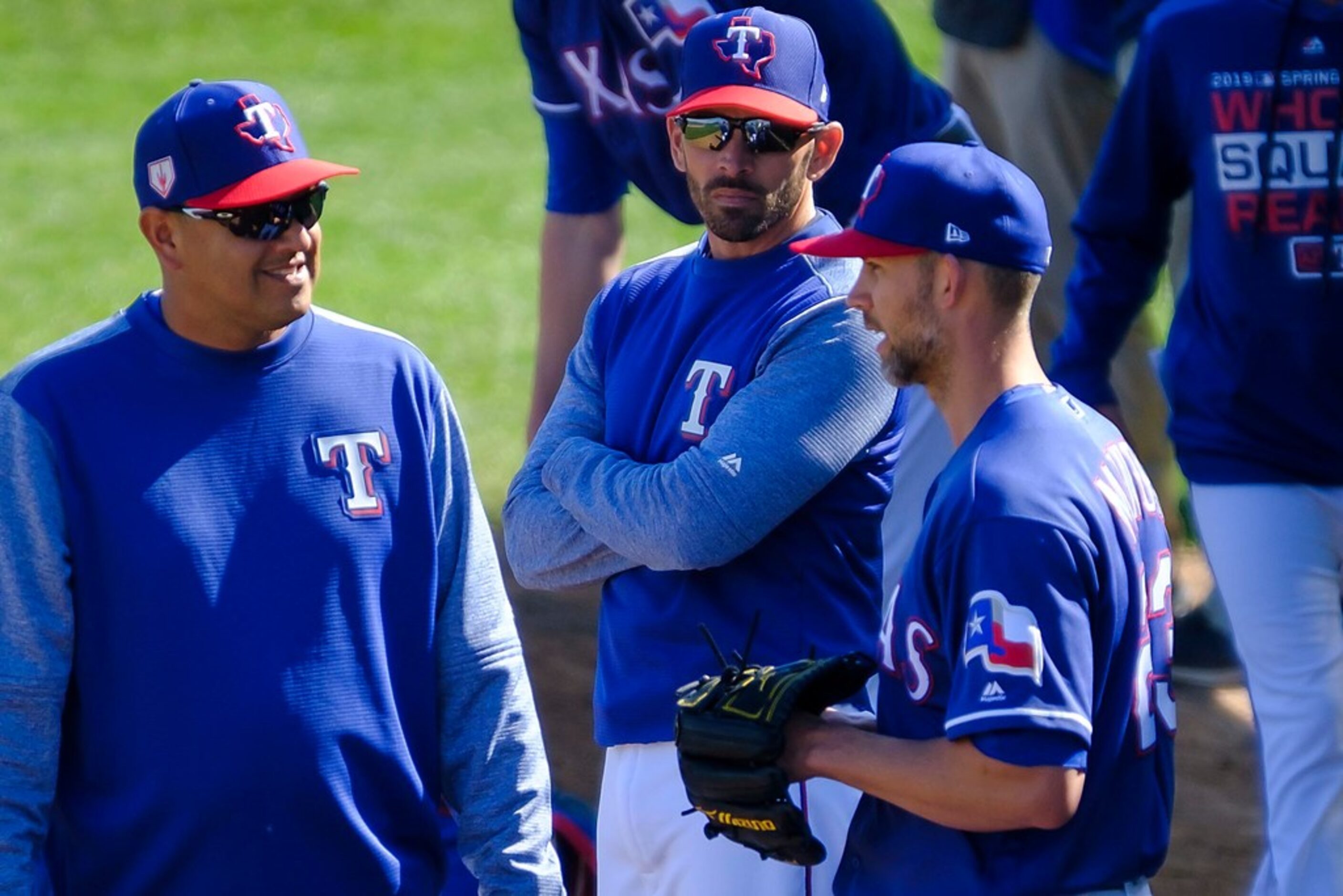 Texas Rangers manager Chris Woodward (center) listens in as pitching coach Julio Rangel...