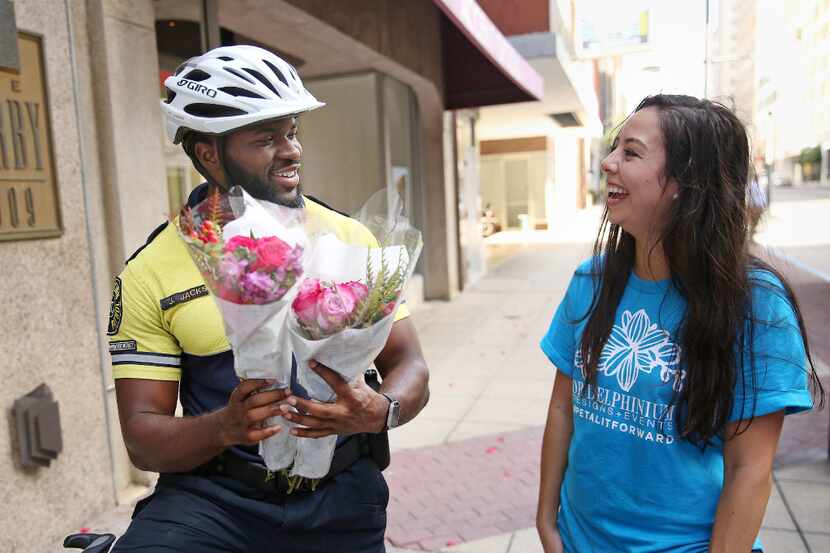 Downtown safety patrolman Jerrole Jackson (left), receives two bouquets of flowers from Kate...