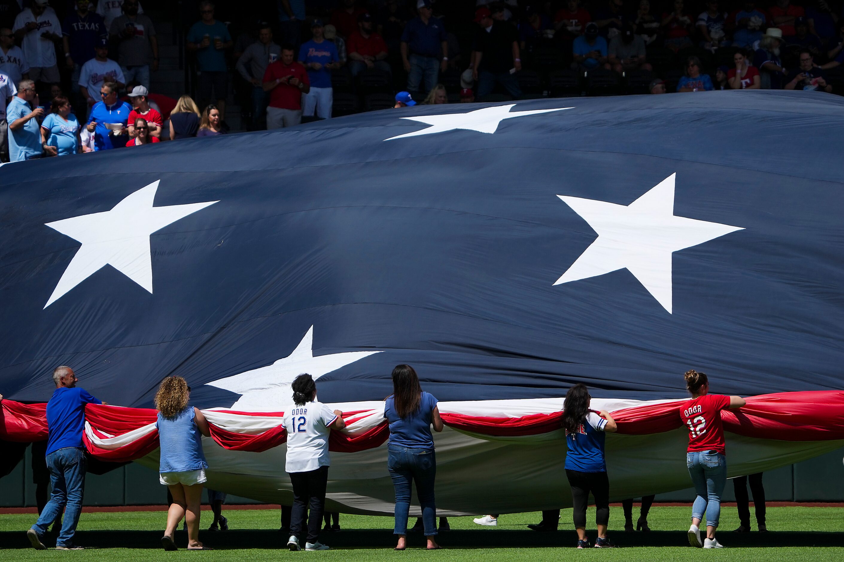 A large flag is unfurled in the outfield for the national anthem before the Texas Rangers...