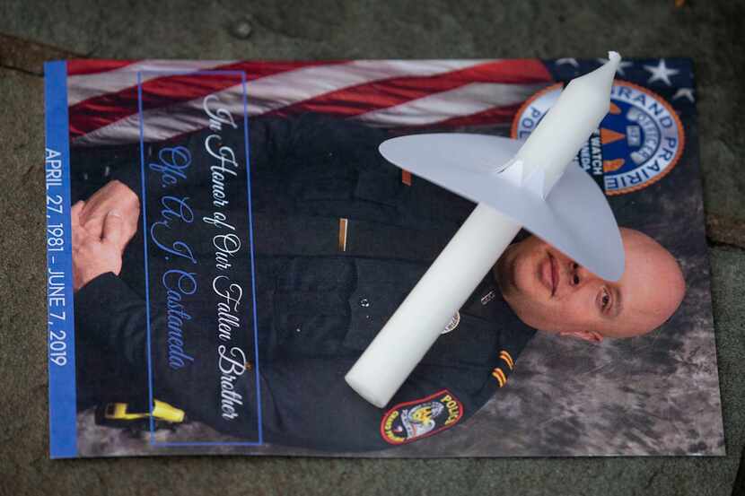 Candles and photos of Grand Prairie police Officer Albert "A.J." Castaneda were distributed...