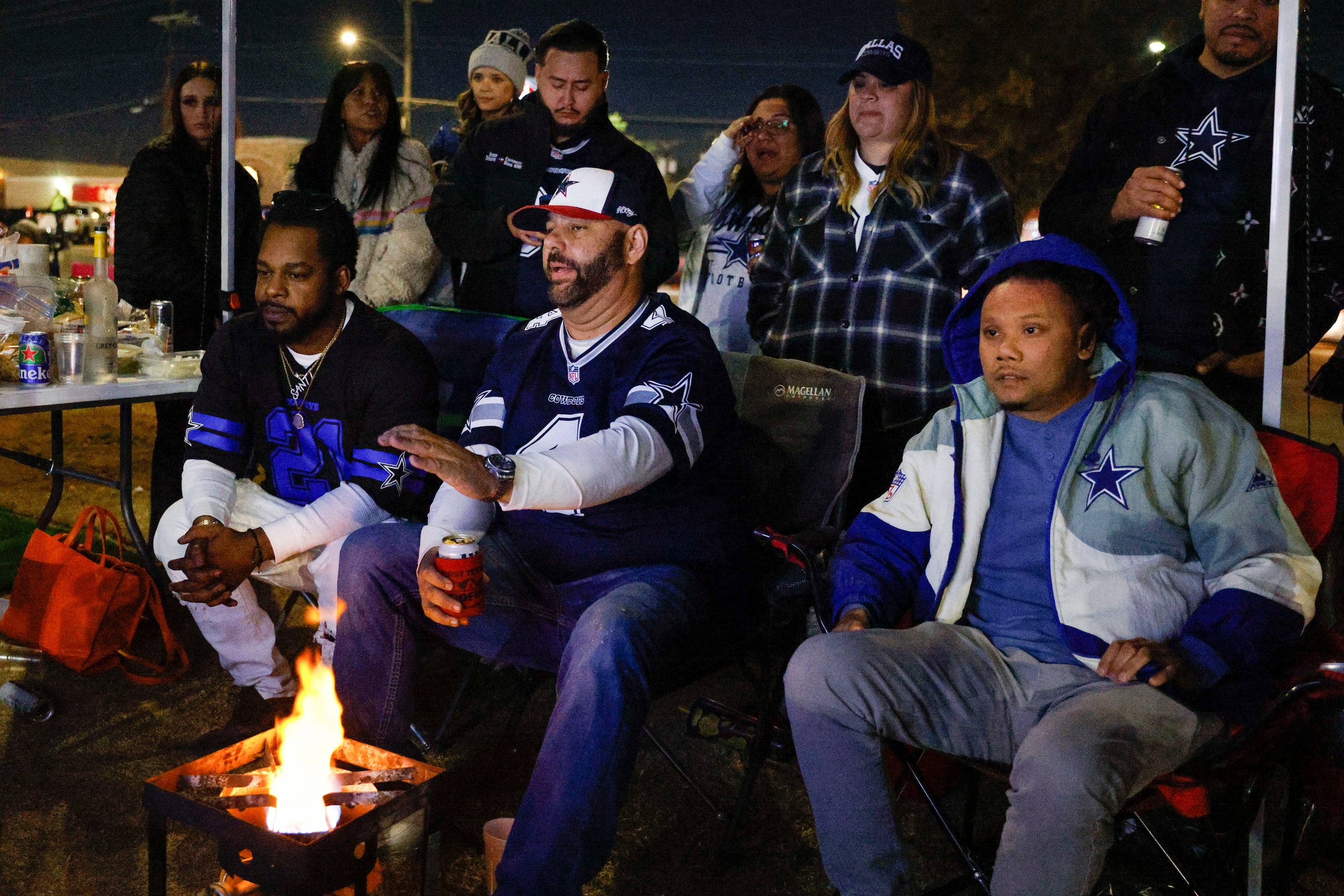 Santiago Lopez (left), Doug Maloney (center) and Max Manikhouth stay warm over a fire during...