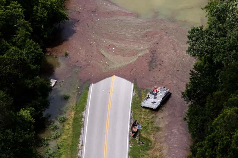
Boats rest where the pavement ends as flood waters from Joe Pool Lake covers a roadway in...