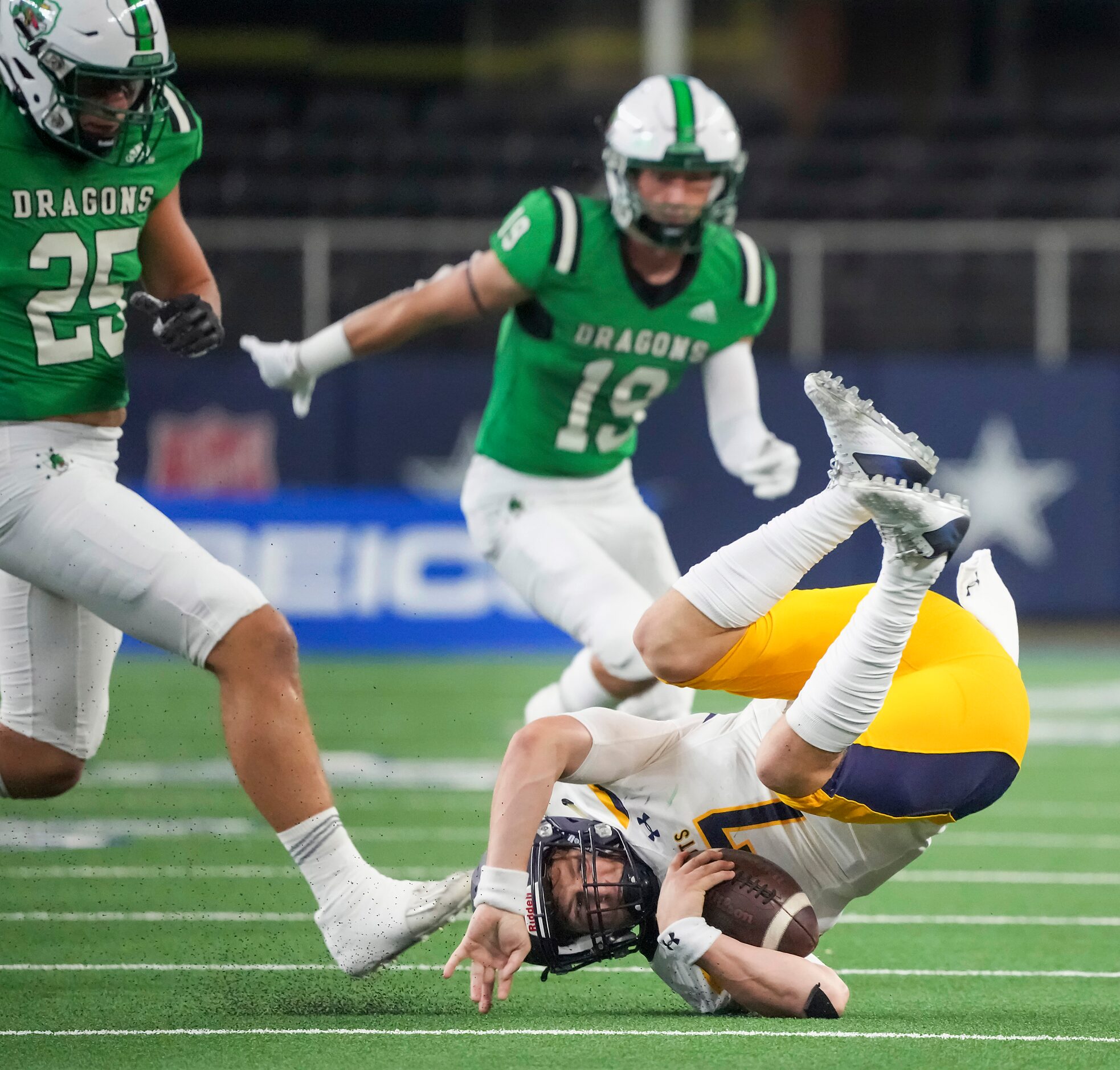 Highland Park quarterback  Brennan Storer (7) tumbles to the turf as he is upended in front...