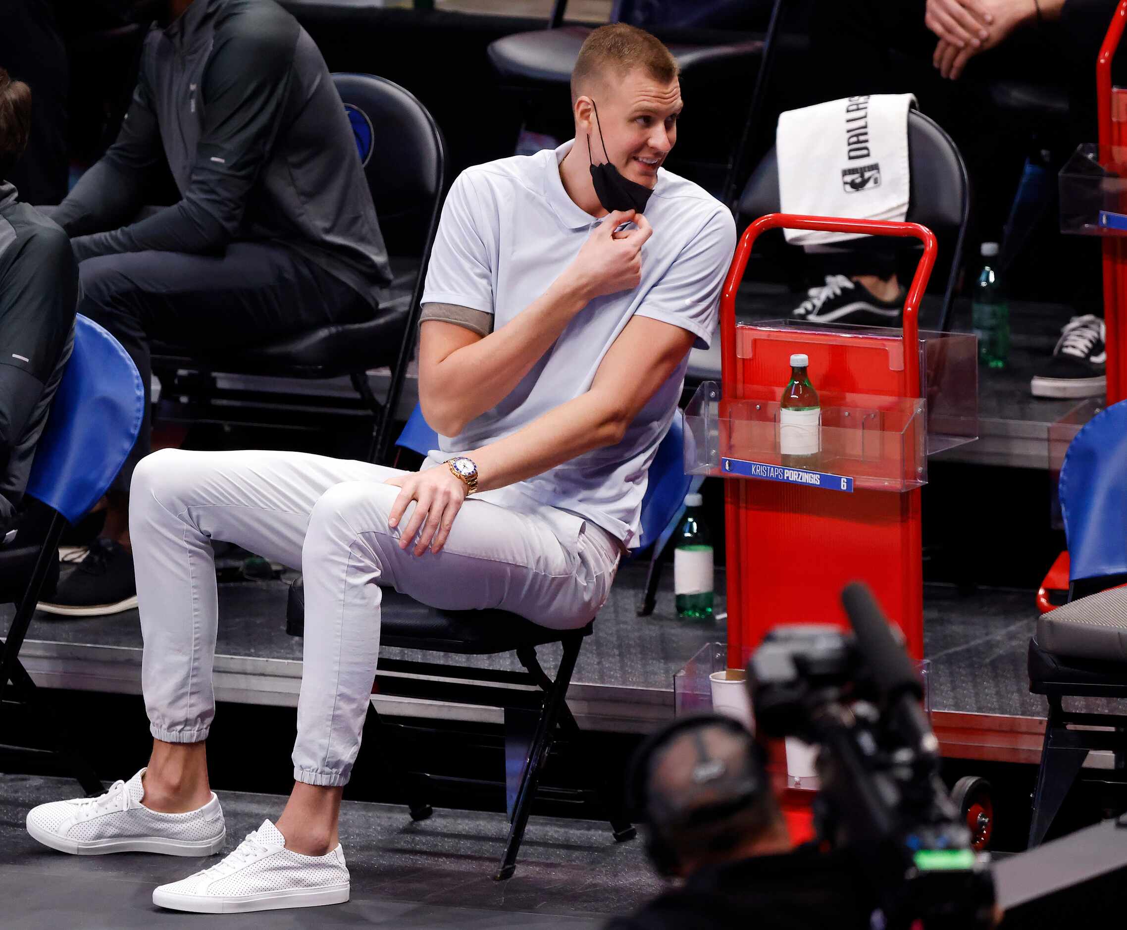 Dallas Mavericks injured center Kristaps Porzingis laughs with his teammates during the...