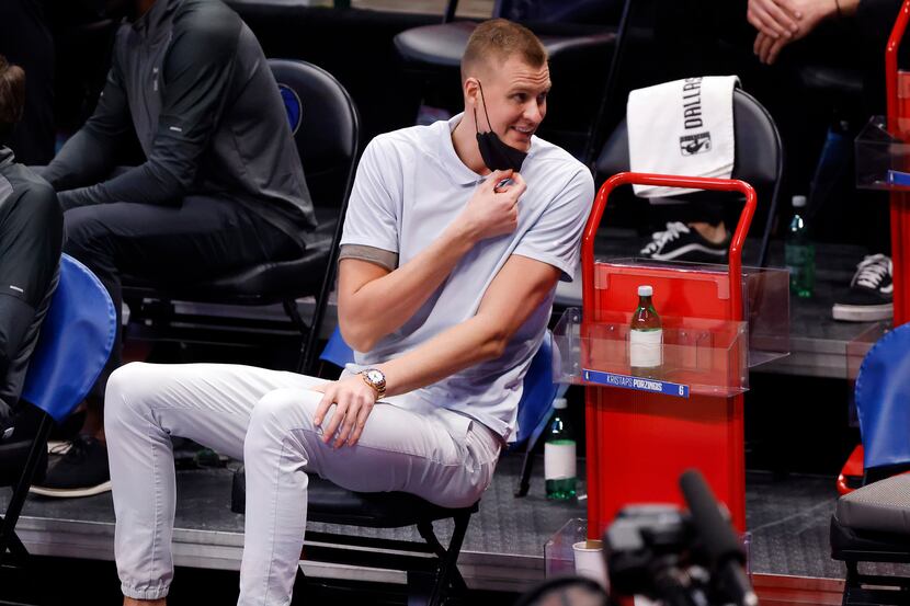 Dallas Mavericks injured center Kristaps Porzingis laughs with his teammates during the...