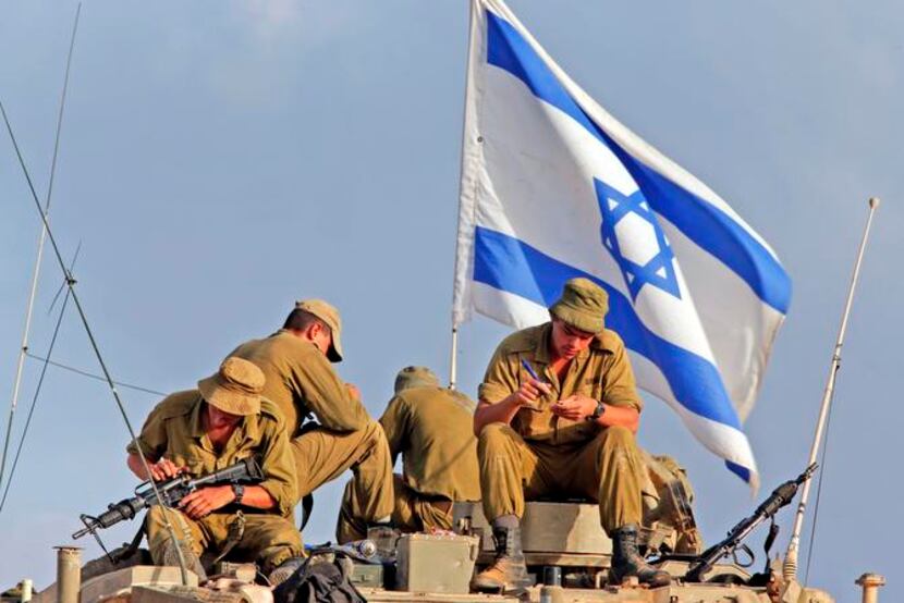 
Israeli soldiers sat on their armored personnel carrier as they cleaned their weapons at a...