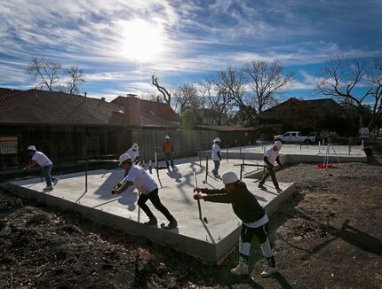 Workers push bars to raise the concrete slab at a home construction site in University Park....